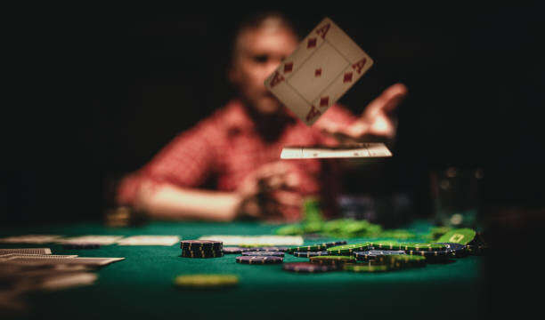 One mature man playing poker late by night, throwing playing cards on table.